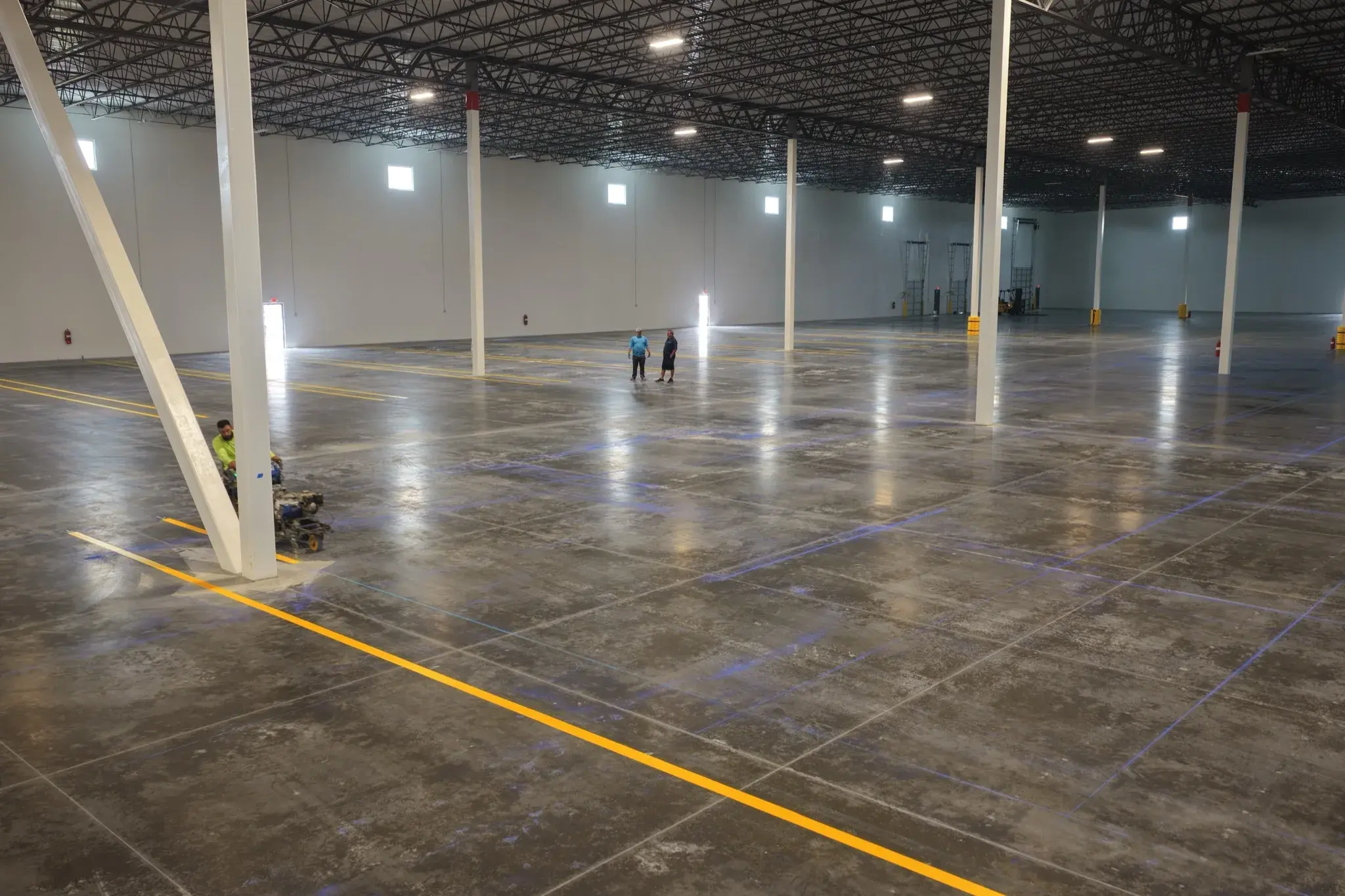Radiant Striping crew applying yellow safety line striping inside the 1-800-PACK-RAT warehouse in Tampa