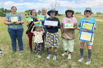 A group of people holding up their paintings 
