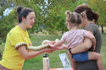 A mom and her kid petting a snake 