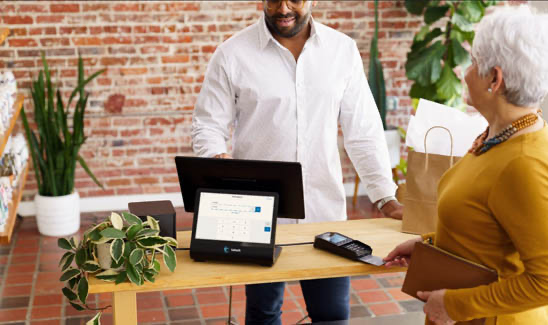 Small business owner using modern POS while checking out customer.