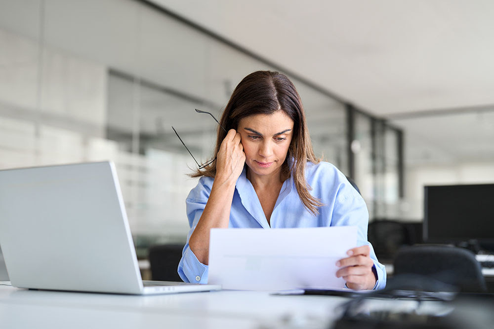 A woman is looking at a bill and looks frustrated. She