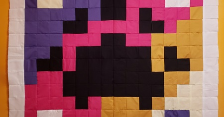 Sewn quilt of colourful squares of cotton and silk made to look like a QR code.
