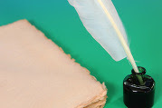 Quill pen in an inkwell next to a stack of paper
