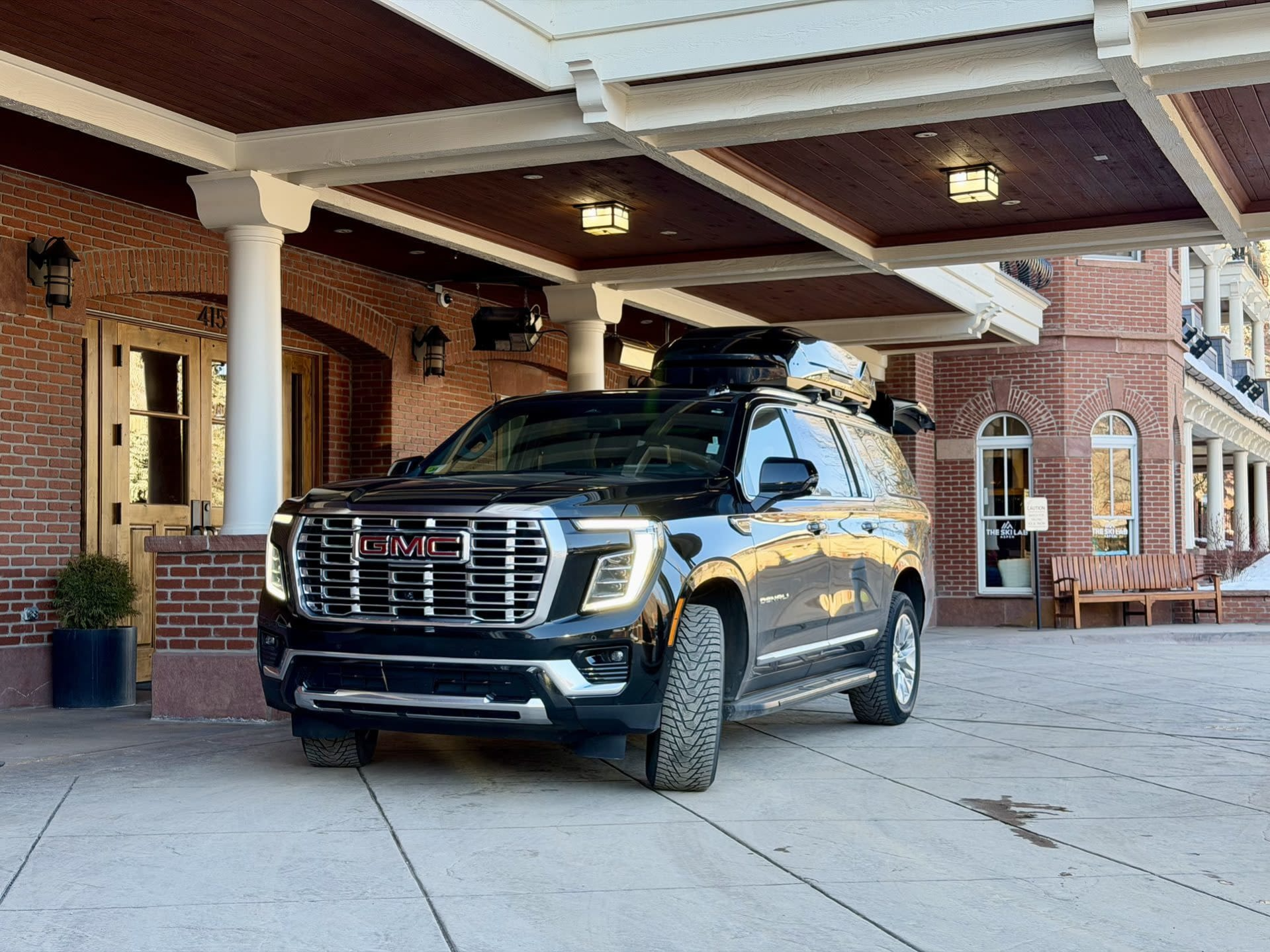 Blue Sky Limo GMC Yukon with a rooftop cargo box at an Aspen hotel