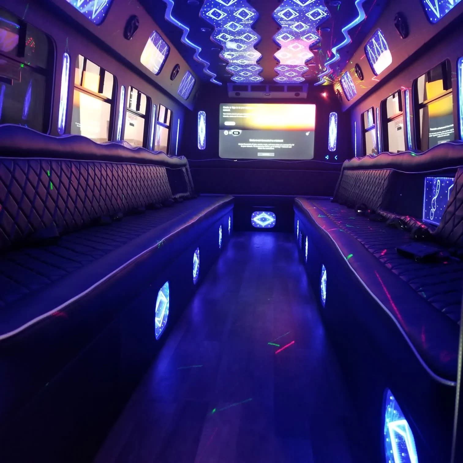 Party bus interior with black lounge seating and purple ceiling lights