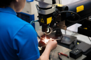 Worker in a blue shirt welding repair mold and die part by Laser welding machine in factory.