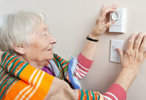 senior adjusting the thermostat