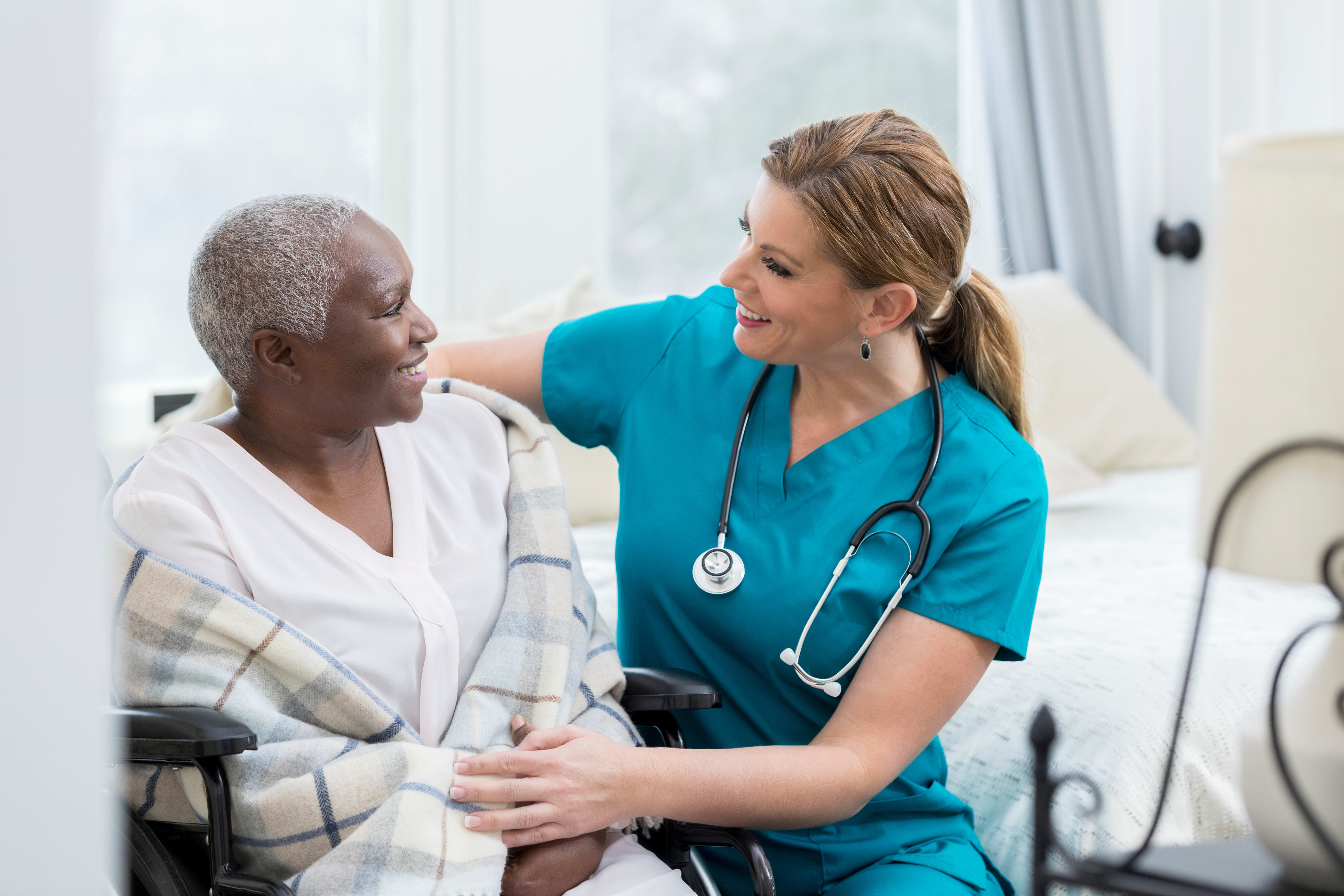 Senior patient sits talking with nurse.