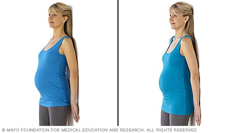 Estiramiento en el embarazo: mujer embarazada realiza ejercicio de inclinación pélvica de pie