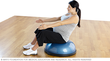 Pregnant person doing a v-sit seated on a balance trainer
