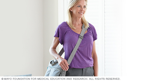 Photo of a woman carrying a large purse by its shoulder strap across her body.