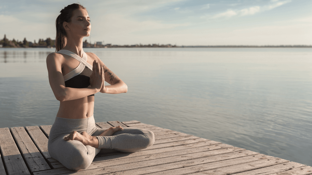 woman meditating near river bank
