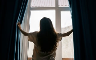 אישה פותחת וילון האפלה