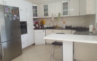 מטבח מודרני עם ארונות לבנים ומכשירי חשמל