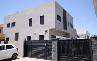 בית מודרני עם חלונות תריסים ושער שחור