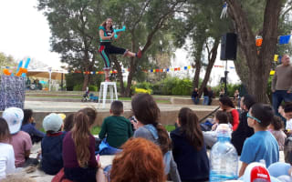 אישה על כיסא עם בלונים, ילדים יושבים מסביב