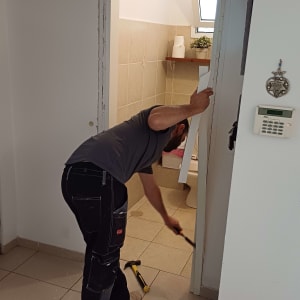 אדם מתקין דלת בחדר אמבטיה