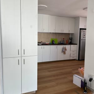 מטבח עם ארונות לבנים, מכשירי חשמל וניקוי