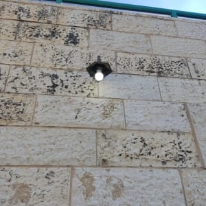 מנורת קיר חיצונית דולקת על קיר אבן