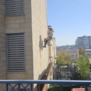 אדם תלוי על חבל בצד בניין גבוה