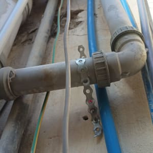 צינורות פלסטיק מחוברים עם מחבר מתכת על קיר