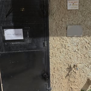 דלת מתכת שחורה על קיר חיצוני עם שלט קטן