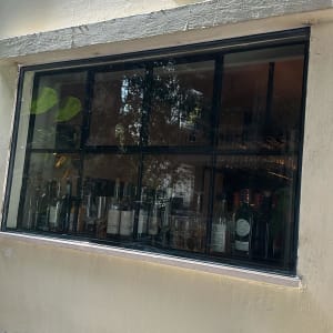 חלון זכוכית עם בקבוקי משקאות וכוסות בפנים