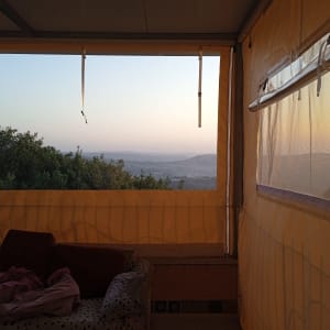 מרפסת עם סוככים צהובים ושקופים, נוף הררי ברקע