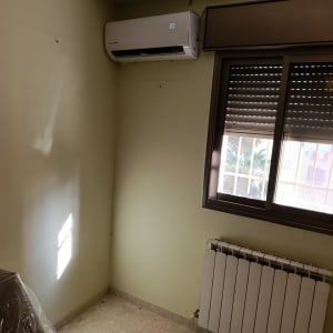 מזגן עילי מותקן בפינת חדר מעל רדיאטור וליד חלון