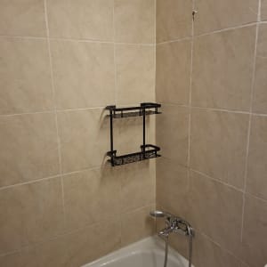 מדף מתכת מותקן על קיר אריחים באמבטיה