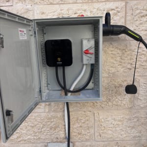 ארון חשמל פתוח עם כבלים וקיר אבן