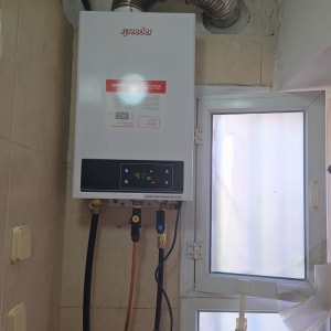 דוד גז מותקן על קיר עם צינורות חיבור