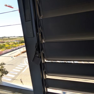 תריסים אפורים עם נוף חיצוני של רחוב ועגורן