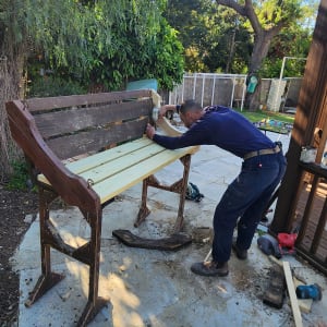 אדם עובד על ספסל עץ בחוץ עם כלים