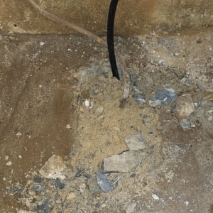 צינור שחור יוצא מהרצפה עם חול ואבנים