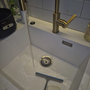 ברז זהב זורם בכיור עם מגב וספוג