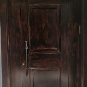 דלת עץ כהה עם ידית מתכת על רקע קיר בהיר