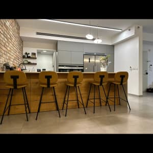 חמישה כיסאות בר מרופדים מול דלפק עץ במטבח מודרני