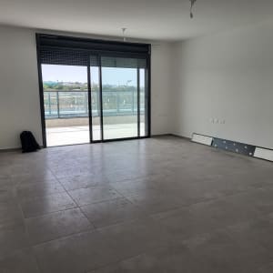 חדר ריק עם רצפת אריחים, חלון גדול ודלת זכוכית