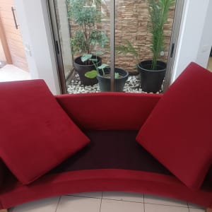 ספה אדומה עם כריות בחדר עם צמחים