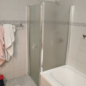 מקלחון זכוכית בחדר אמבטיה עם מגבות תלויות