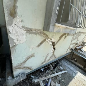 קיר עם סדקים ותיקונים, צינור מתכת, פסולת בנייה