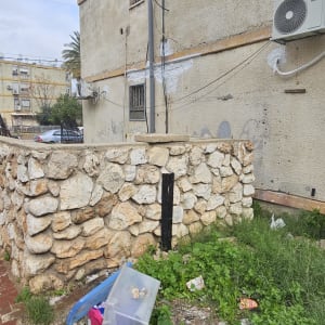 קיר אבן עם צמחייה ופסולת בחוץ