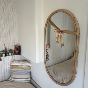 מראה אובלית תלויה על הקיר עם מסגרת עץ