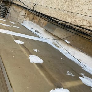 כתמי צבע לבן על גג מתכת ליד קיר