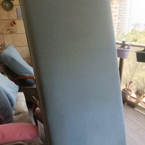 מזרן עומד על מרפסת עם צמחים ברקע