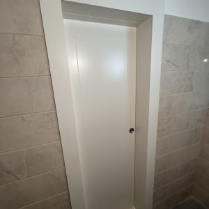 דלת לבנה בחדר אמבטיה עם אריחים