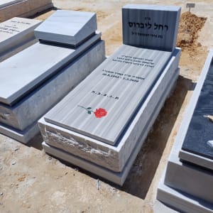 מצבות עם כיתוב ופרח אדום על אבן