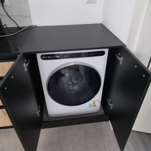 מכונת כביסה בתוך ארון פתוח עם דלתות שחורות