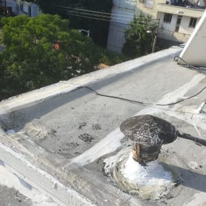 גג עם חומרי איטום לבנים סביב צינור מתכת.